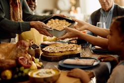 Close up of senior woman serving food to her family while celebrating Thanksgiving at home. 