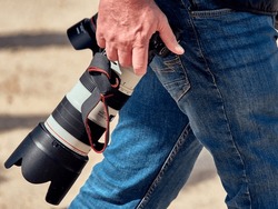 Capture the perfect shot with this stunning photo of a photographer carrying a large and heavy camera lens.