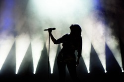 Vocalist singing to microphone. Singer in silhouette.