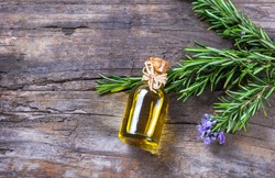 Top view Bottle glass of essential rosemary oil with rosemary branch and flower on wooden rustic background. herbal oil concept 