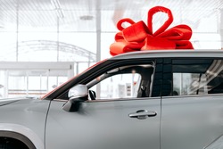 The new car is wrapped in a red bow. Beautiful gift concept 