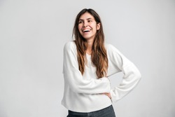 Portrait of happy lively young beautiful hipster woman standing and looking away with toothy smile. Indoor studio shot isolated on white background 