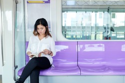 young adult girl reading a book on metro train transit, sky train Purple Line in Thailand
