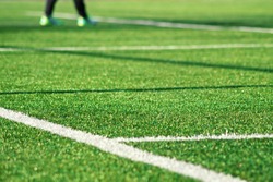 Artificial green grass  with white stripe of soccer field. White line on green grass a field of play. Fake Grass used on sports fields for soccer and football. Closed-up of artificial grass background
