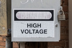 A securely locked utility box with High Voltage written on it and the word Danger faded from the sun