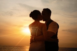 Senior business man and his wife hugging and kissing on celebration event at the yacht deck,Silhouette romance scene marriage anniversary over sunset, luxury and happiness moment