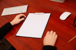 Woman signing a document or writing correspondence with a close up view of his hand with the pen and sheet of notepaper on a desk top.  