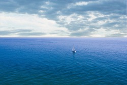 Small sailboat entering the immensity of the ocean. Aerial shot