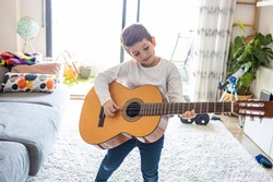 Funny kid playing guitar at home