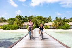 Mother and son riding their bikes on a walkway in the Maldives