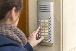 Woman talking on the intercom and presses the button