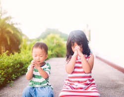 Little sister praying with her baby brother.Prayer kids pray for help.Christian little girl and toddler boy at home in Japan.Family with children at park.Christianity, Love, trust and tenderness.