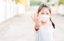 Coronavirus Covid-19.Stay at home Stay safe concept.Little chinese girl wearing mask for protect.show stop hands gesture for stop corona virus outbreak.Coronavirus pandemic virus symptoms.Home school.
