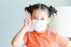 Coronavirus and Air pollution pm2.5 concept.Little chinese girl wearing mask for quarantine and show fighting gesture with Covid-19 virus outbreak.Wuhan coronavirus and epidemic virus symptoms.