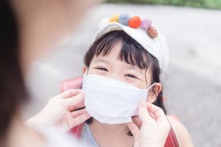 Coronavirus Covid-19 and face mask, Reopen school, Back to school,Education heathcare medical.Japanese mother wearing fabric face mask for kid girl daughter when go back to school.New normal Stay safe