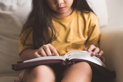 Asian kid girl read bible study.Worship at home.Sunday school.Bible on kid hands.Family christian ,Reading bible study.Hands holding on a Holy Bible.faith, spirituality and religion.child Pray online.