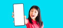 Happy kid tween teen asian girl holding phone smartphone mock up showing white blank display for advertising, text, promotion.Asian kid girl smile and excited face.banner background.Digital phone app.