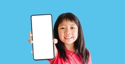 Happy kid tween teen asian girl holding phone smartphone mock up showing white blank display for advertising, text, promotion.Asian kid girl online learning app.banner background.Digital phone app.