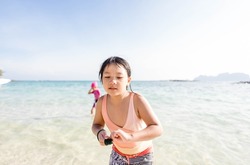 Asian girl tweens swimsuit running on clear water ocean sea on the beach.Vacation relax travel concept.Save ocean day environment.Skincare lotion sunscreen.kid teens girl on beach in summer vacation.