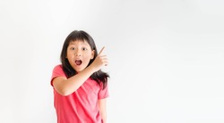 tween kid girl with pink shirt pointing finger with excited face looking camera.Advertising ad promotion.Asian student teen girl attention finger point.Education isolated background.portrait girl.