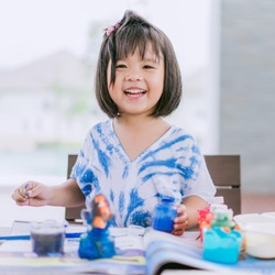 Portrait of adorable little asian girl holding a paintbrush and working on a painting for art class in school.Confidence Positivity Freedom Be Creative Concept.