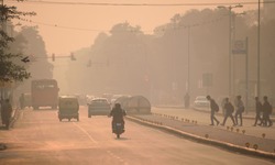 Vehicles and people moving in the streets amidst heavy smog.