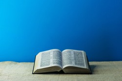 Bible and a crucifix on a old table. Beautiful blue background.Religion concept.