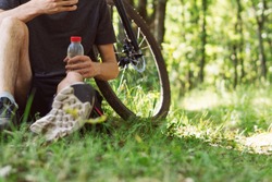 Young male cyclist drinks water . Cycling in the Park and forest. Healthy and active lifestyle