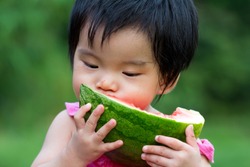 Little Asian baby eating watermelon in park
