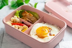 Kid school lunch bento box set of grilled fish, egg, rice and vegetables