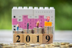 Miniature people : Close up of miniature shopper and display shelf figure on coins stacks on 2019 wood block and calendar as backdrop. Festive, holiday, year end discount,and boxing day.