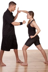 Barefoot athletic young woman and man practising kick boxing blocking and throwing punches as they train together
