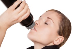 Sporty thirsty young woman drinking from a water bottle, closeup
