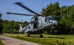 Military Helicopter Merlin EH101 landing in confined woodland area on a training mission.
