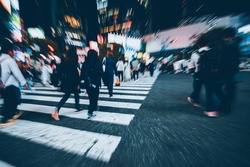 Abstract Blur crowd of anonymous people hurry and rush to cross the street at Shibuya zebra pedestrian crossing or scramble crosswalk during evening rush hour. Urban lifestyle and rushing concept.