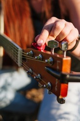 Young girl tuning the guitar. Macro of musical instrument tuning
