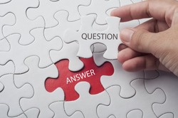 Hand holding piece of jigsaw puzzle with word question & answer.