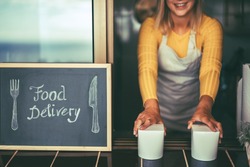 Young woman serving healthy take away food inside restaurant - Happy girl working inside delivery food ghost kitchen - Online business order service concept - Focus on hands