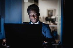 African american man working at night time inside modern office - Focus on face