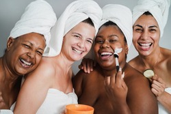 Multigenerational women having fun applying face beauty masks on their face - Main focus on caucasian woman face