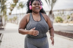 Curvy african woman jogging outdoor at city park - Focus on face