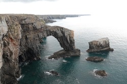 Green bridge of Wales. Limestone arch dipping from the cliff into the sea in Pembrokeshire. Largest in the UK. Formed by coastal erosion of softer materials around it. 