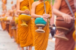 Buddhist Monks Line up in Row Waiting for Buddhism People to Give Alms Bowl in Thai Temple.  Blur Effect added in this image.