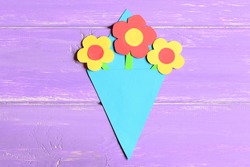Making paper flowers crafts for mother's day or birthday. Step. Preschool art lesson. Colored paper bouquet isolated on a wooden background. Creative activities for preschoolers. Top view