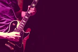 Guitarist on stage for background, soft and blur concept. Close up hand playing guitar. young musician playing guitar, live music background.Band performs on stage, rock music concert.