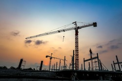 New construction site with crane and mechanical equipments on sunset background.