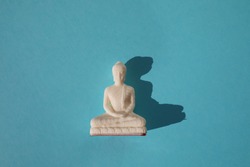 Buddha statue on blue background with copy space. Essential accessory for mindfulness or meditation. Isolated.