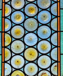 Traditional French chateau window made of circular tinted glass forming an interesting pattern and texture suitable for backgrounds or wallpapers