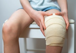 Child knee with adhesive and gauze bandage.