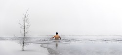 Man going ice swimming into a frozen lake in winter